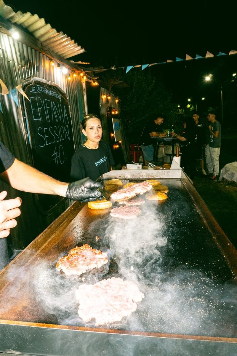 Plancha humeante con hamburguesas durante un evento nocturno